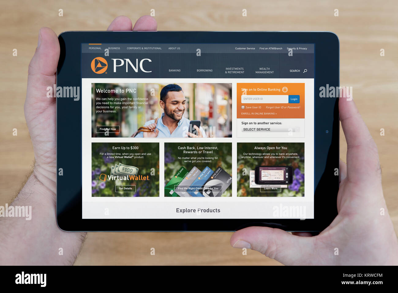 Ein Mann schaut auf die PNC Financial Services Website auf seinem iPad tablet device, Schuß gegen einen hölzernen Tisch top Hintergrund (nur redaktionelle Nutzung) Stockfoto