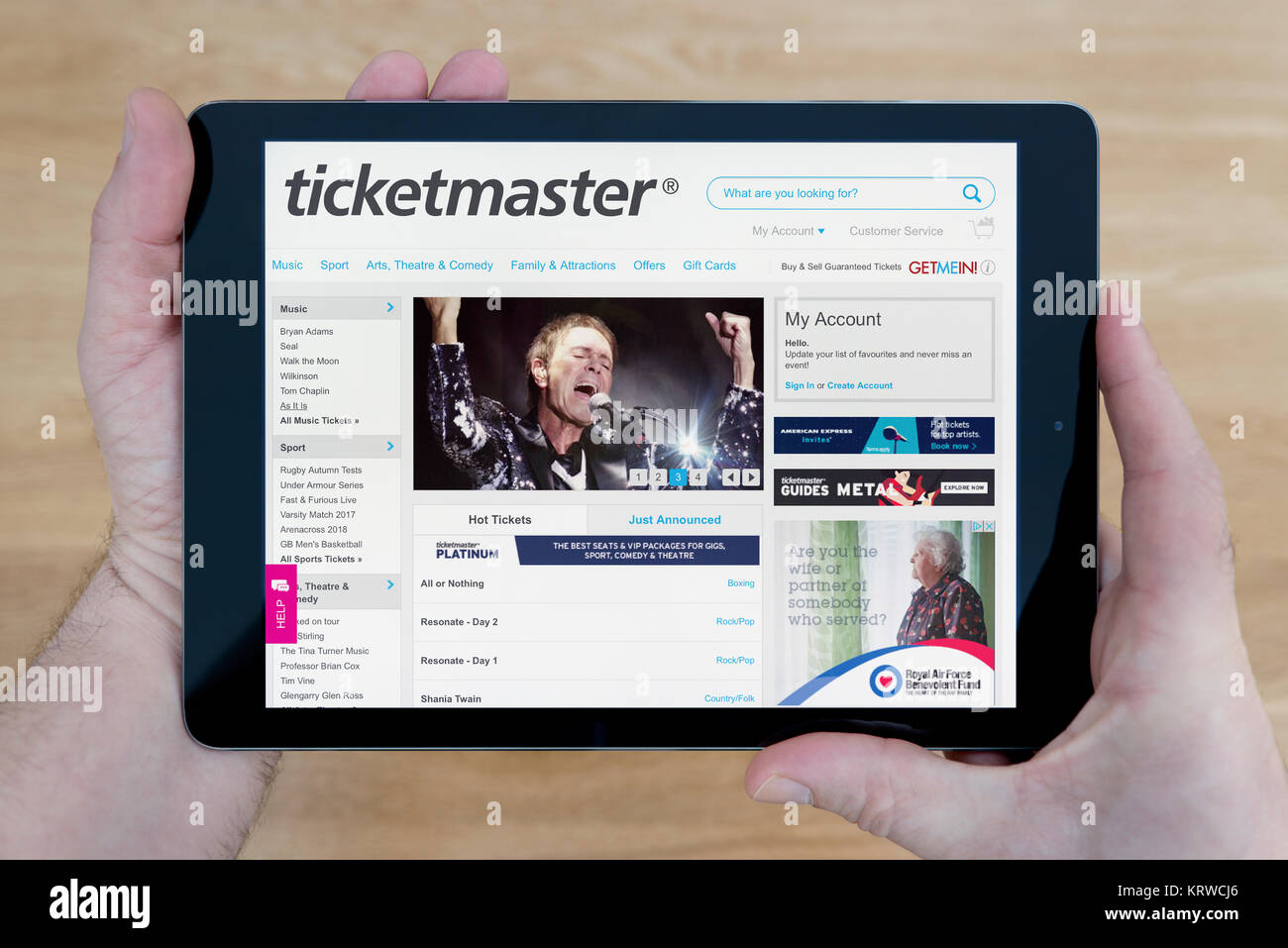 Ein Mann schaut auf der Website von Ticketmaster auf seinem iPad tablet device, Schuß gegen einen hölzernen Tisch top Hintergrund (nur redaktionelle Nutzung) Stockfoto