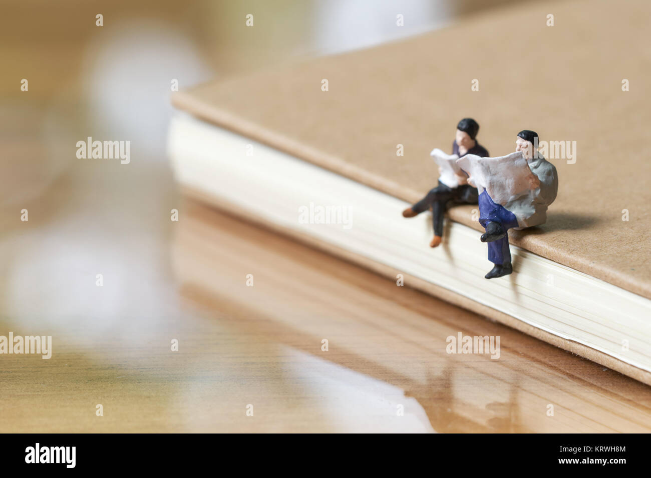 Miniatur 2 Personen sitzen, lesen Zeitung auf Hinweis die Verwendung als Hintergrund Business Konzept mit Kopie Platz buchen. Stockfoto