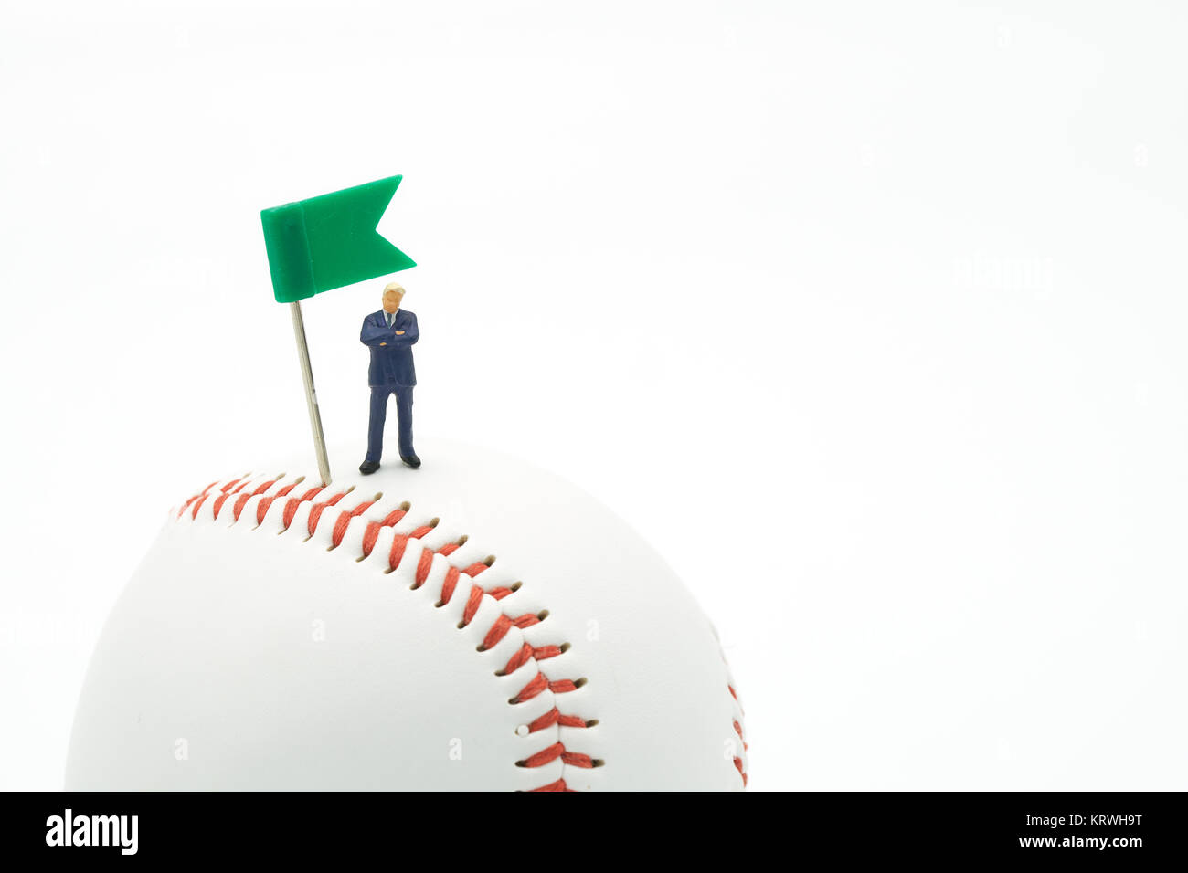 Miniatur Menschen Unternehmer stehen mit Grüne Flagge Pin auf Baseball auf einen weißen Hintergrund und roten Ziernähten Baseball. Als Hintergrund Strategie Konzept Stockfoto