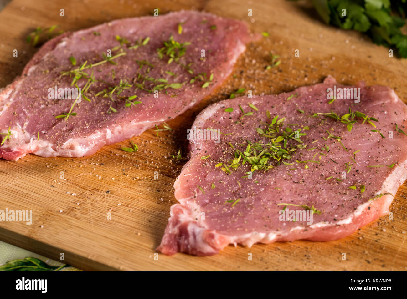 Schweinekoteletts auf einem Schneidebrett mit frischen Kräutern. Selektiver Fokus Stockfoto
