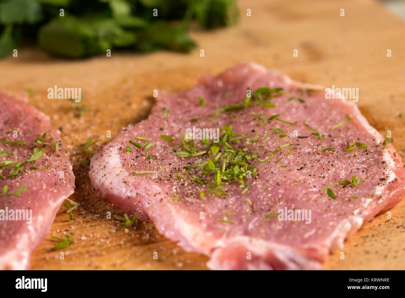 Schweinekoteletts auf einem Schneidebrett mit frischen Kräutern. Selektiver Fokus Stockfoto