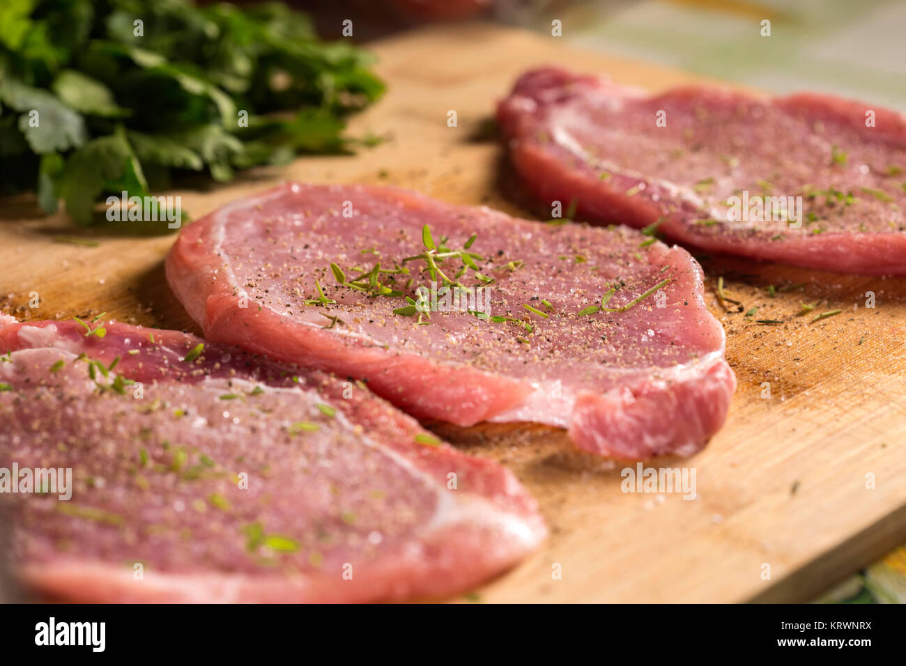 Nahaufnahme von schweinekoteletts auf einem Schneidebrett mit frischen Kräutern. Selektiver Fokus Stockfoto