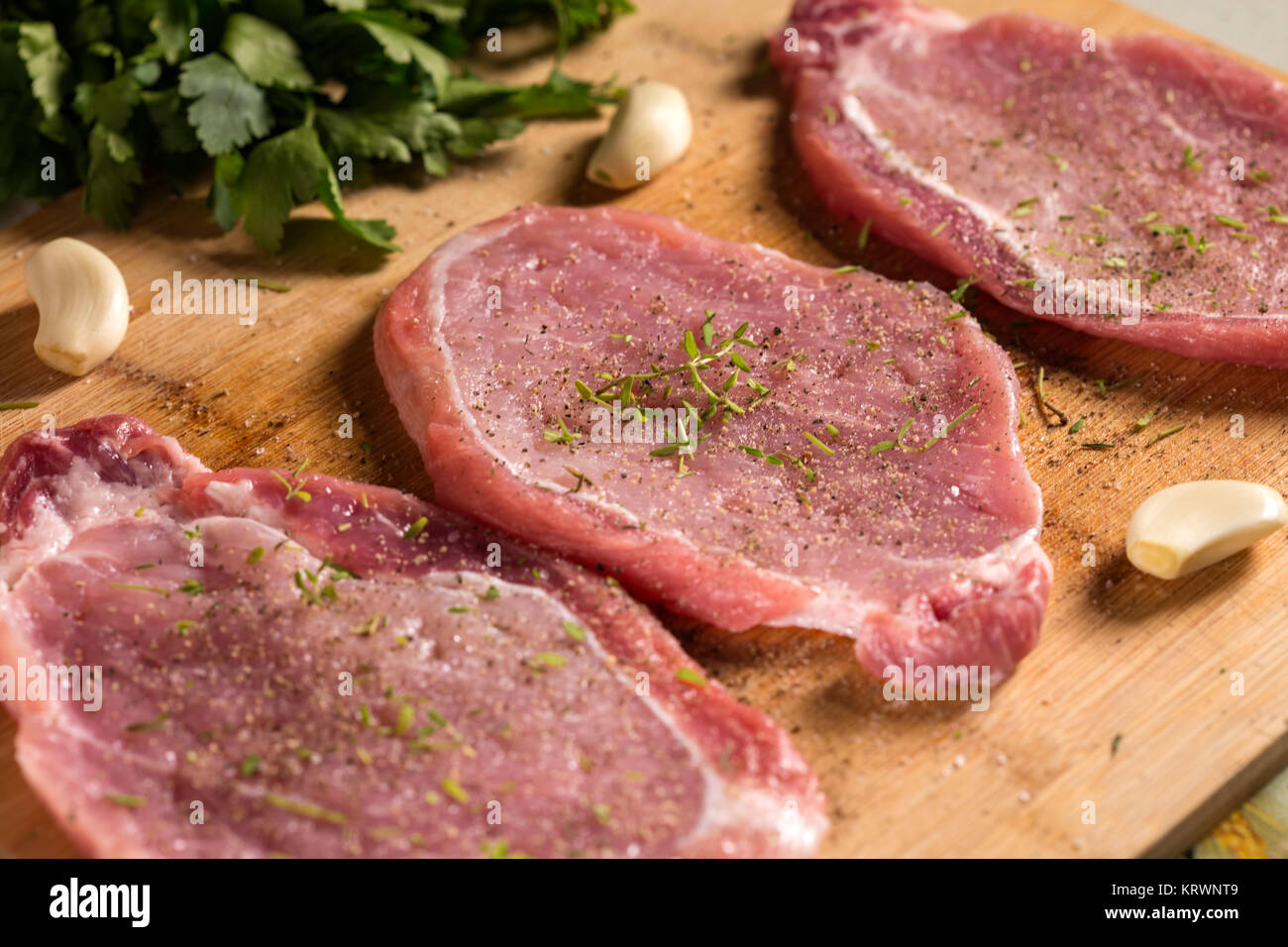 Nahaufnahme von schweinekoteletts auf einem Schneidebrett mit frischen Kräutern. Selektiver Fokus Stockfoto