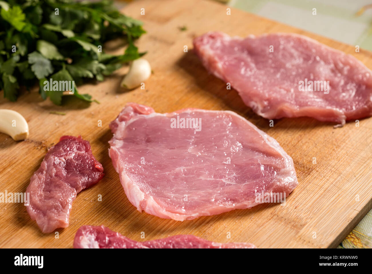 Schweinekoteletts auf einem Schneidebrett mit frischen Kräutern. Selektiver Fokus Stockfoto