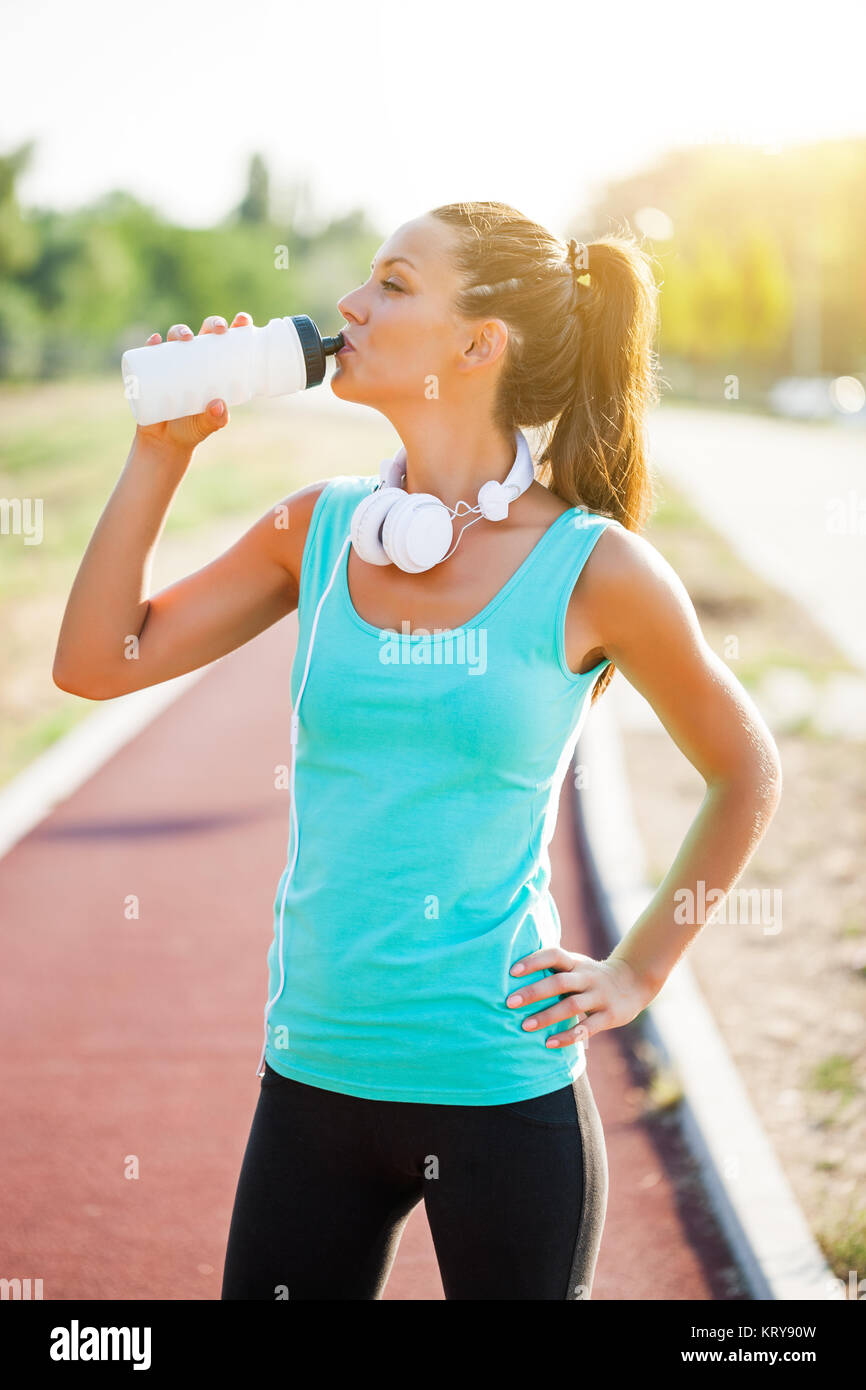 Junge Frau ist Trinkwasser nach dem Joggen an einem sonnigen Tag. Stockfoto