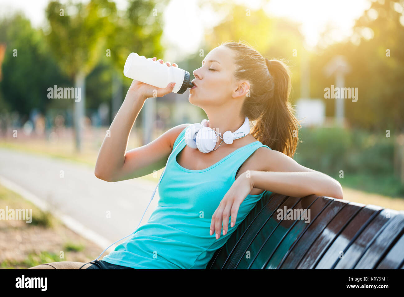 Junge Frau ist entspannend und Trinkwasser nach dem Joggen. Stockfoto