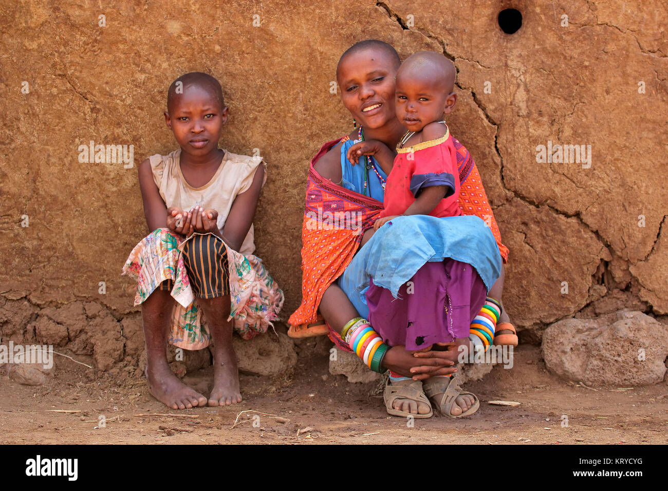 AMBOSELI, Kenia - 31. AUGUST 2013: Unbekannter Massai Frau und ihrer Kinder mit traditionellen Dekorationen und bunte Rote Kleider in einem ländlichen Dorf Stockfoto