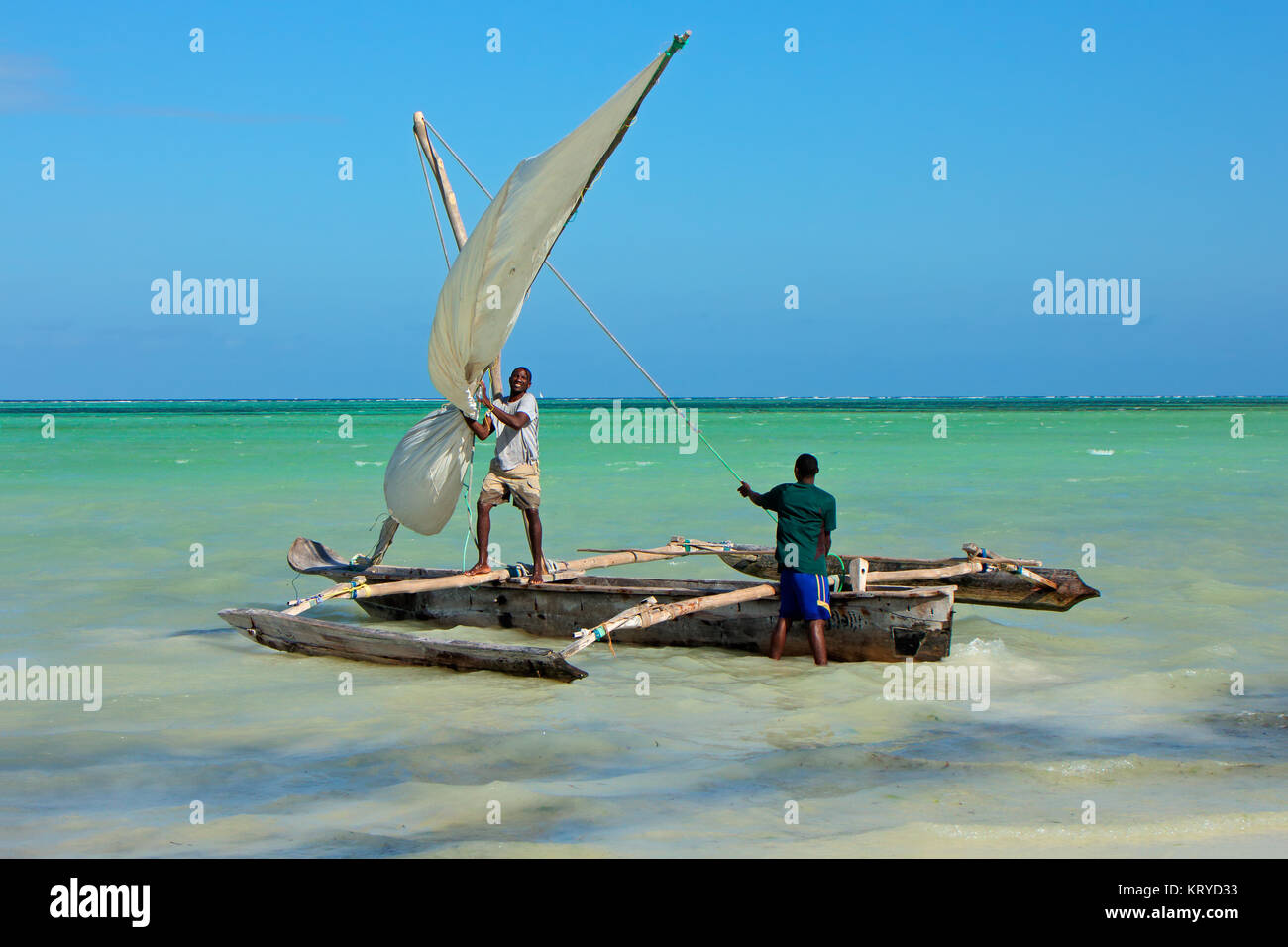 Sansibar, Tansania - Oktober 28, 2014: Unbekannter Männer starten eine hölzerne Segelboot (dhau) auf das klare, türkisfarbene Wasser der Insel Sansibar Stockfoto
