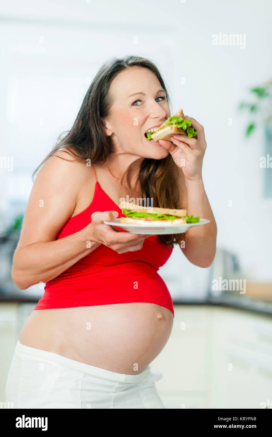Schwangere Frau isst ein Sandwich - schwangere Frau isst ein Sandwich Stockfoto