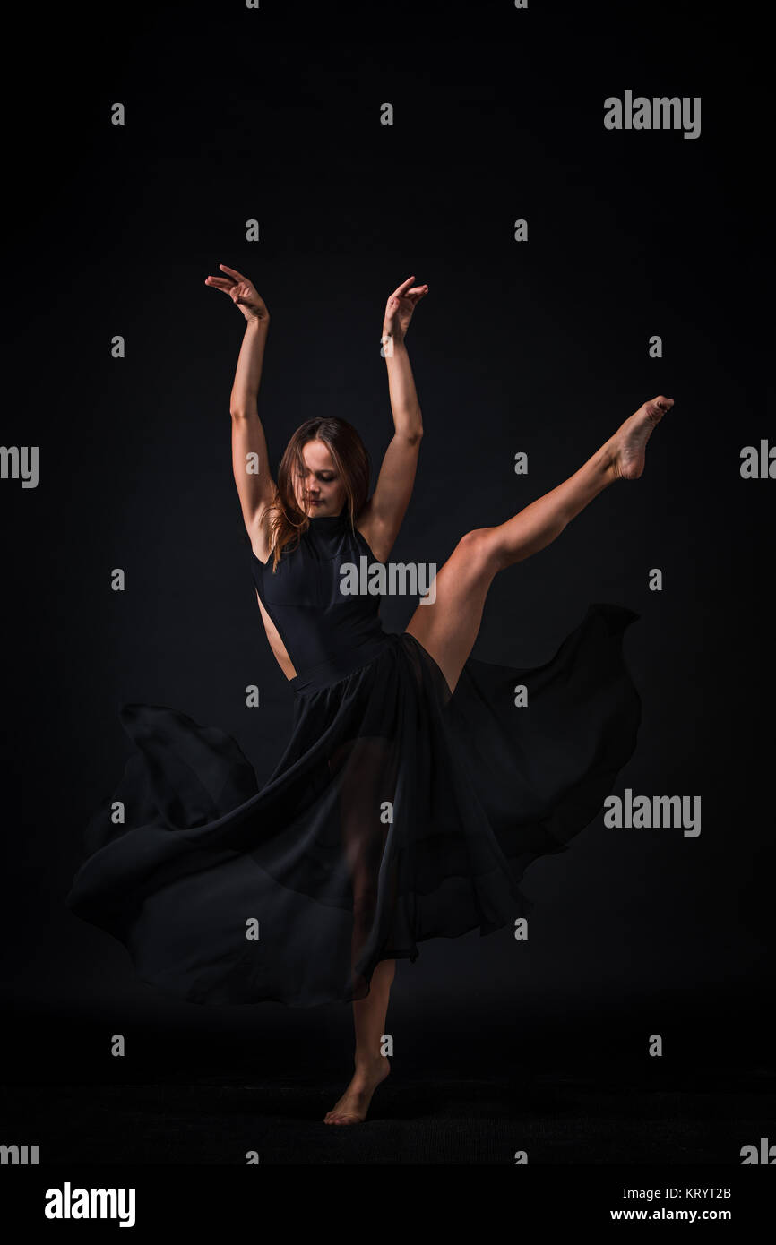 Junge schöne Tänzerin in beige Kleid tanzen auf schwarzem Hintergrund Stockfoto