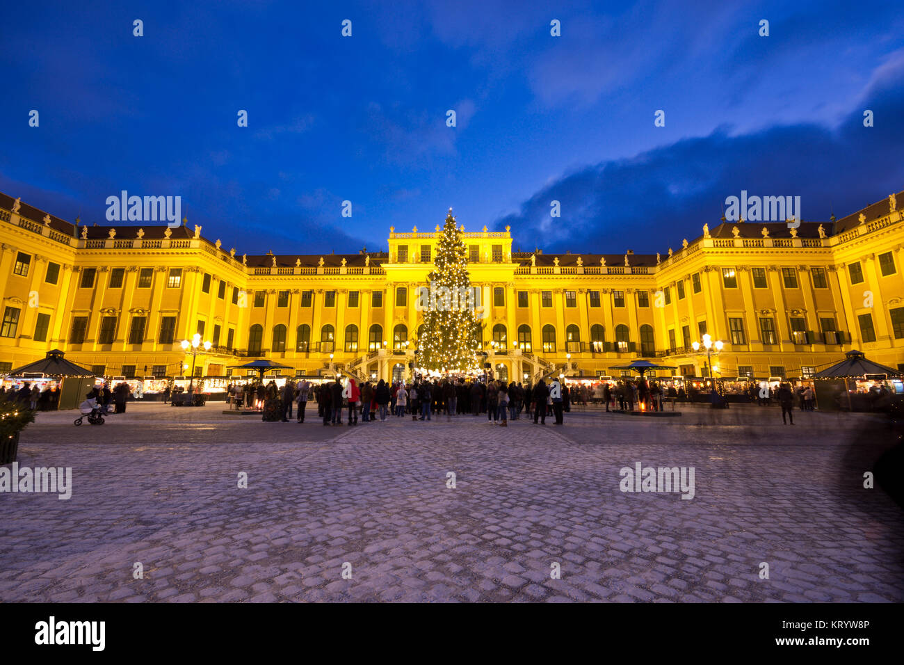 Blick auf das beleuchtete Schloss Schönbrunn in der Weihnachtszeit mit Lichterketten geschmückten Weihnachtsbaum und Markt in der Dämmerung im Advent. Stockfoto