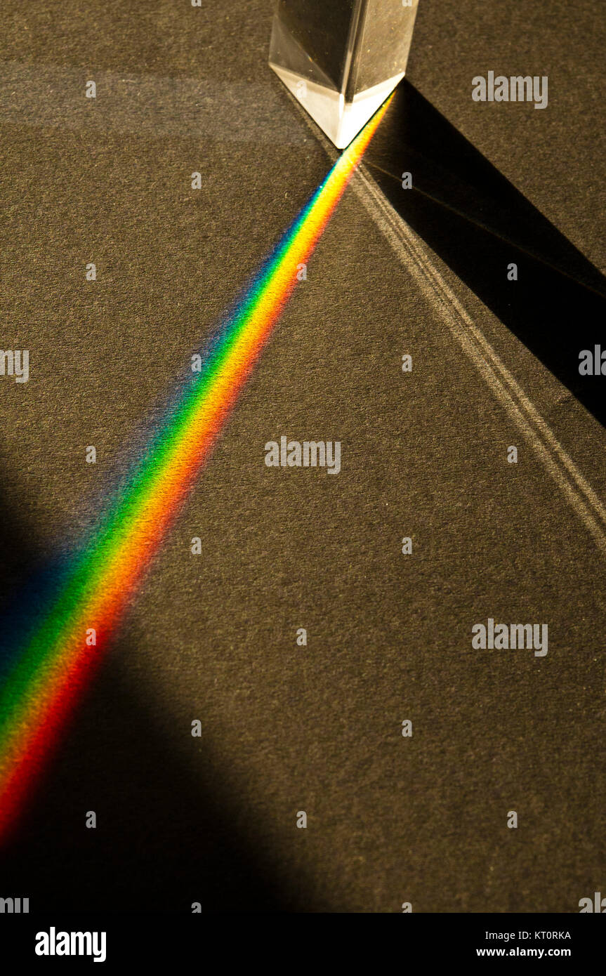 Glasprisma erzeugt einen Regenbogen-Lichteffekt auf einer schwarzen Oberfläche Stockfoto