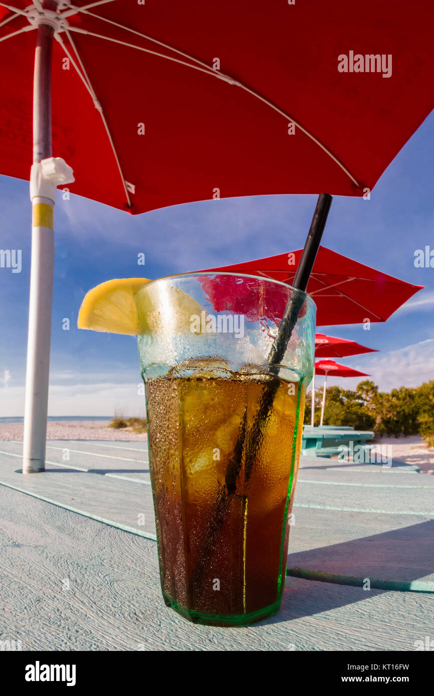 Glas aus Eis kalten Eistee mit Zitrone sitzen am Tisch unter Red Sonnenschirme am South Beach Bar & Grill am Gasparilla Island, Florida Stockfoto