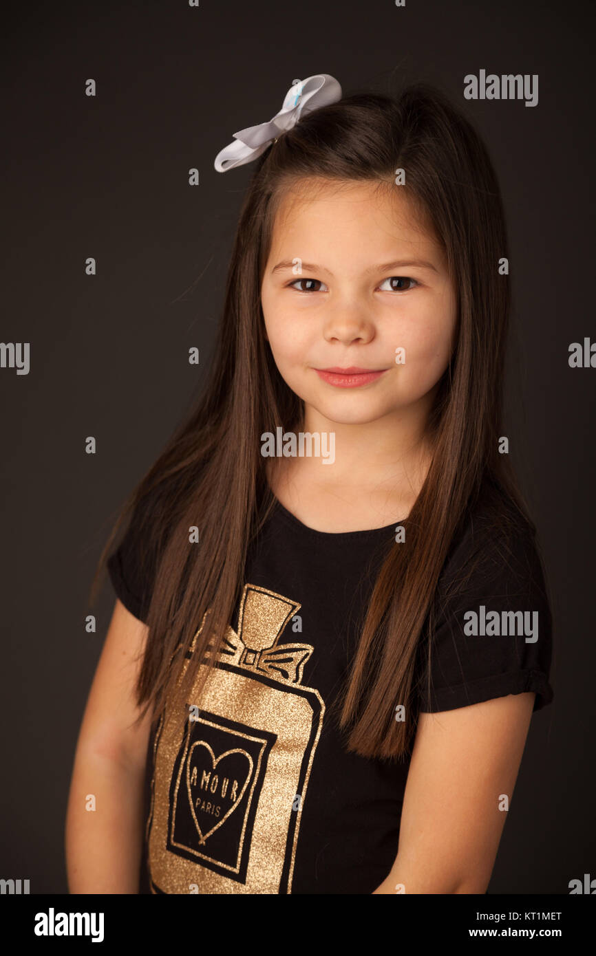 Porträt eines 7 Jahre alten Mädchen mit dunklen Haaren in einem Studio vor einem dunklen Hintergrund. Stockfoto