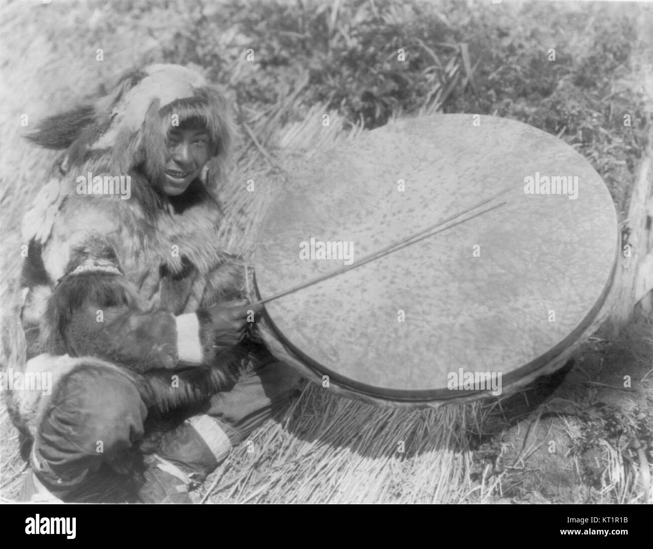 Das Bild mit dem Titel Drummer Nunivak Curtis LOC zeigt einen Drummer der Ureinwohner Alaskas, möglicherweise aus der Region Nunivak Island. Das Foto erfasst die kulturelle Bedeutung des Trommels in den Traditionen der Ureinwohner Alaskas und hebt die Rolle von Musik und Rhythmus im kulturellen Ausdruck und bei Gemeindeversammlungen hervor. Stockfoto