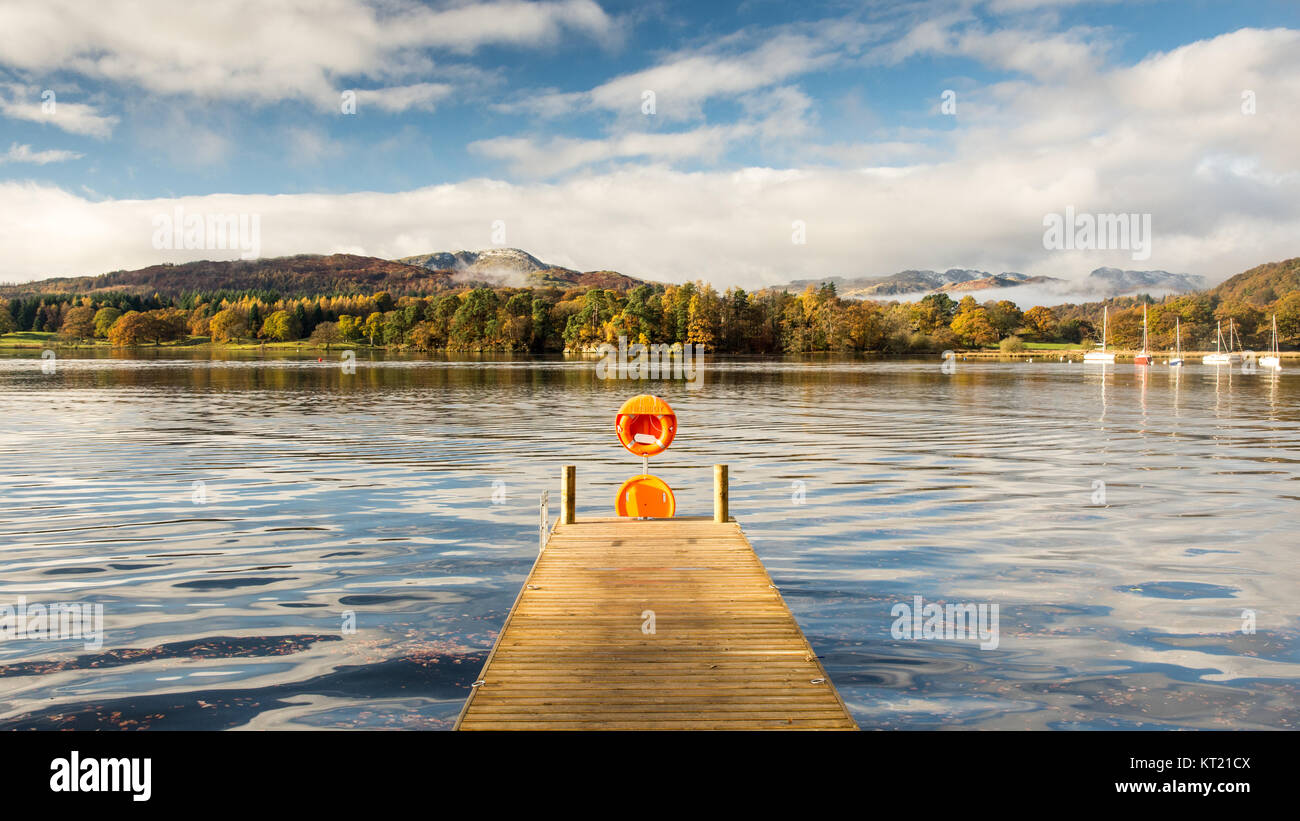 Die Sonne scheint auf einem Pier in Ambleside auf Windermere See, in den Bergen von Langdale und Herbst Wald in England Lake District National Park. Stockfoto