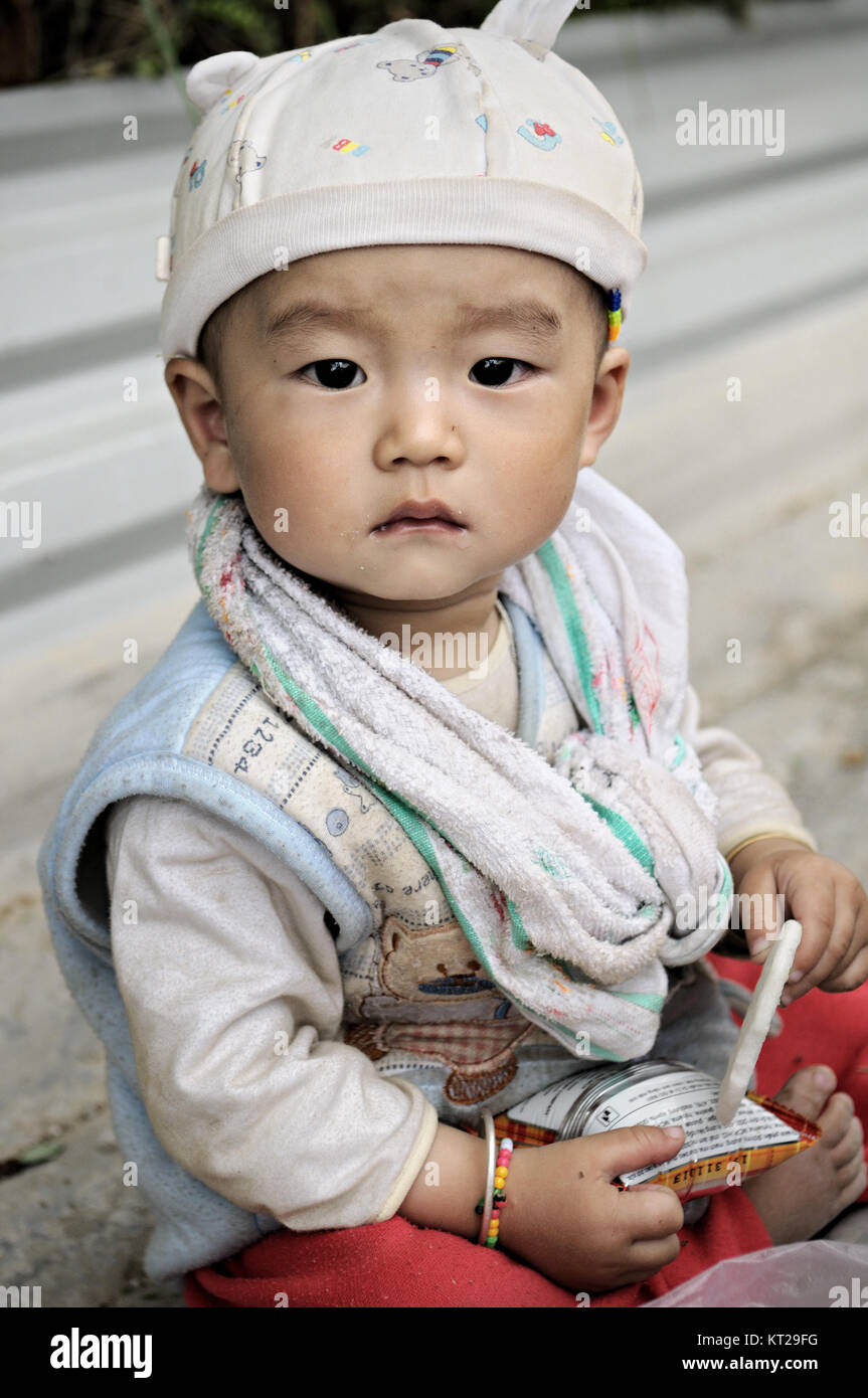 Baby Boy mit einer Kopfbedeckung, Draußen sitzen im Norden Vietnams Stockfoto