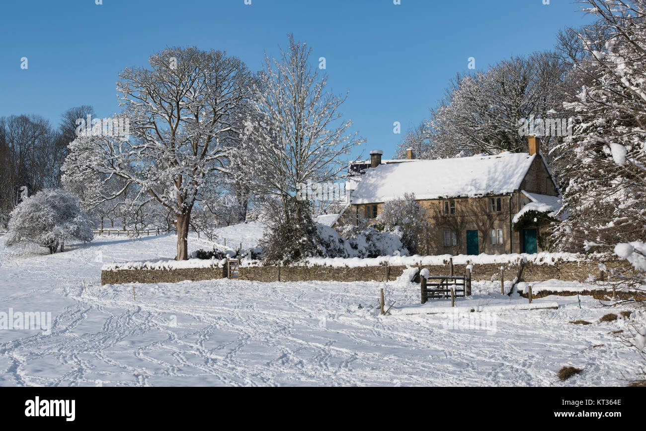 Cotswold Cottage in der Nähe von Turkdean im Schnee mit blauen Himmel im Dezember. Turkdean, Cotswolds, Gloucestershire, England. Panoramablick Stockfoto
