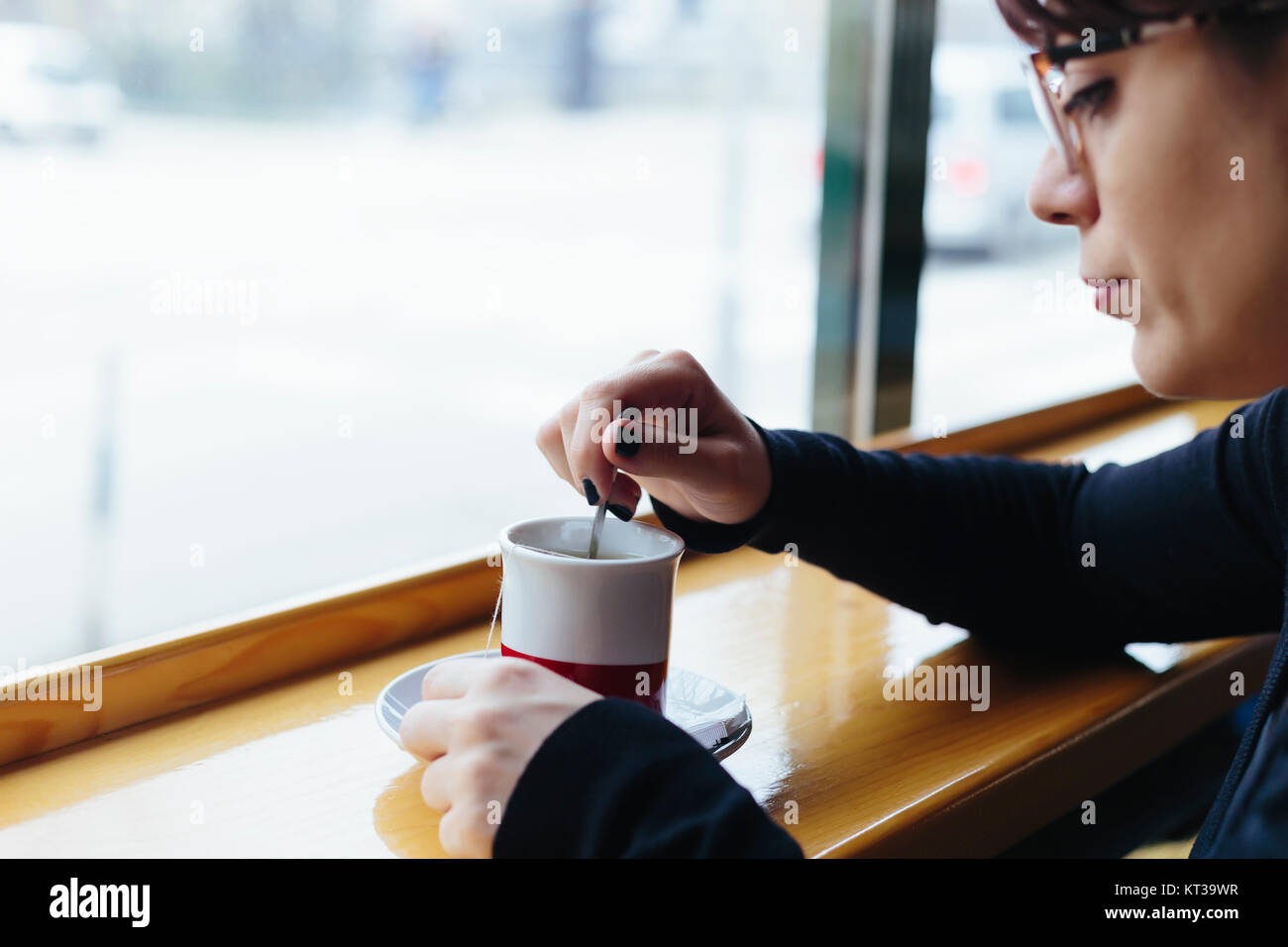 Ein Mädchen sitzt am Fenster Sitz der Coffee Shop, Tee trinken. Stockfoto