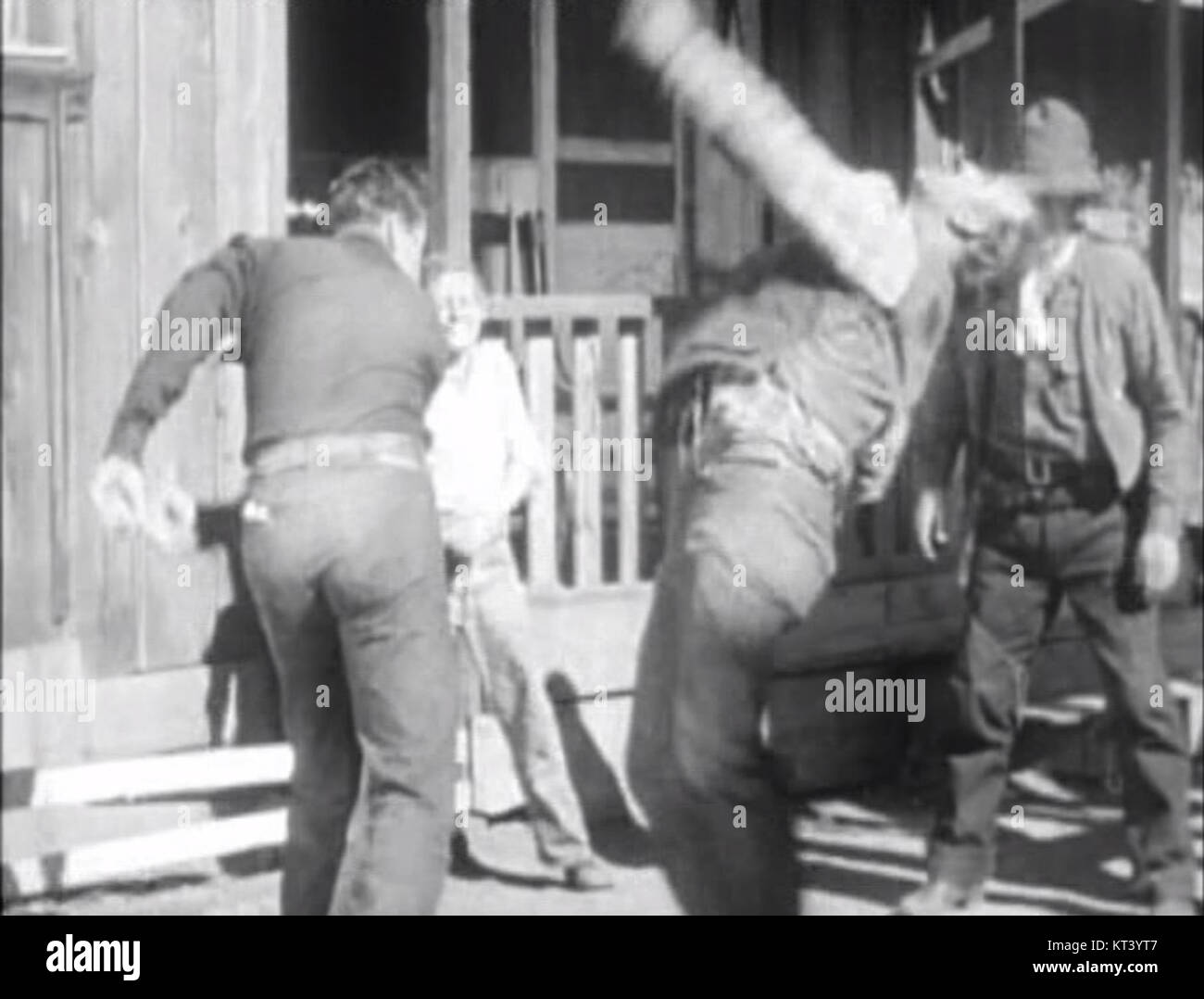 Dieses Bild zeigt John Wayne, der einen Schlag liefert, eine Szene, die seine actiongeladenen Rollen in westlichen Filmen veranschaulicht. Wayne ist bekannt für seine harte Persönlichkeit und wurde zu einer filmischen Ikone des amerikanischen Films. Stockfoto