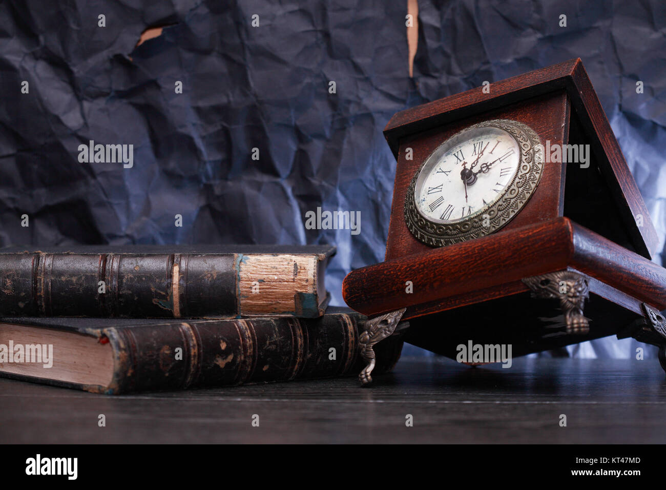 Alte hölzerne Uhr in der Nähe der Bücher auf schöner grauer Hintergrund Stockfoto