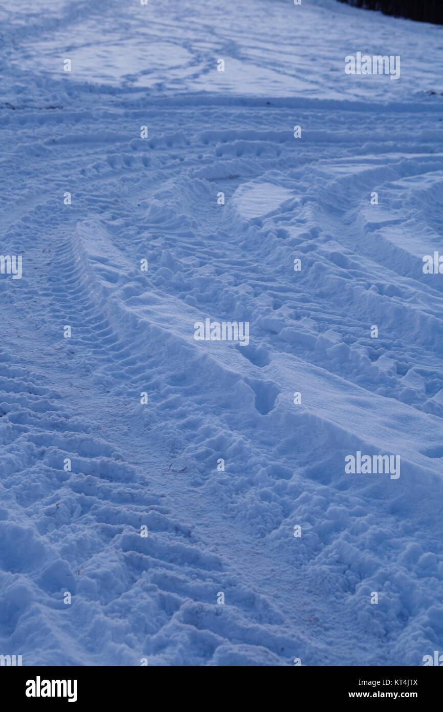 Einige Schleuderspuren führen zu einem snowscape an der Stelle, an der der blaue Stunde am Abend. Stockfoto