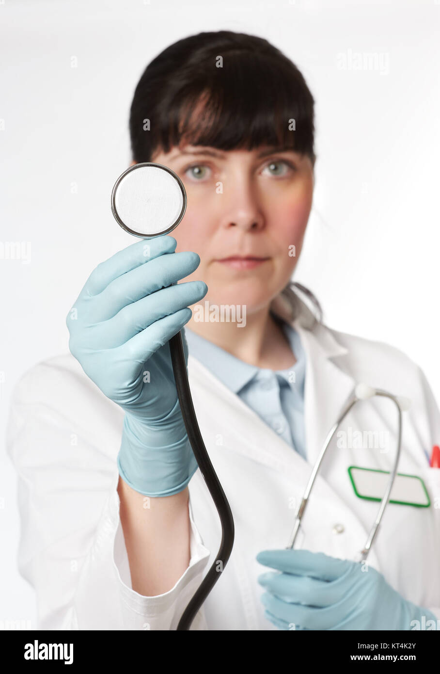 Ärztin mit einem Stethoskop auf weißem Hintergrund. Flache DOF, auf behandschuhte Hand mit Stethoskop konzentrieren. Stockfoto