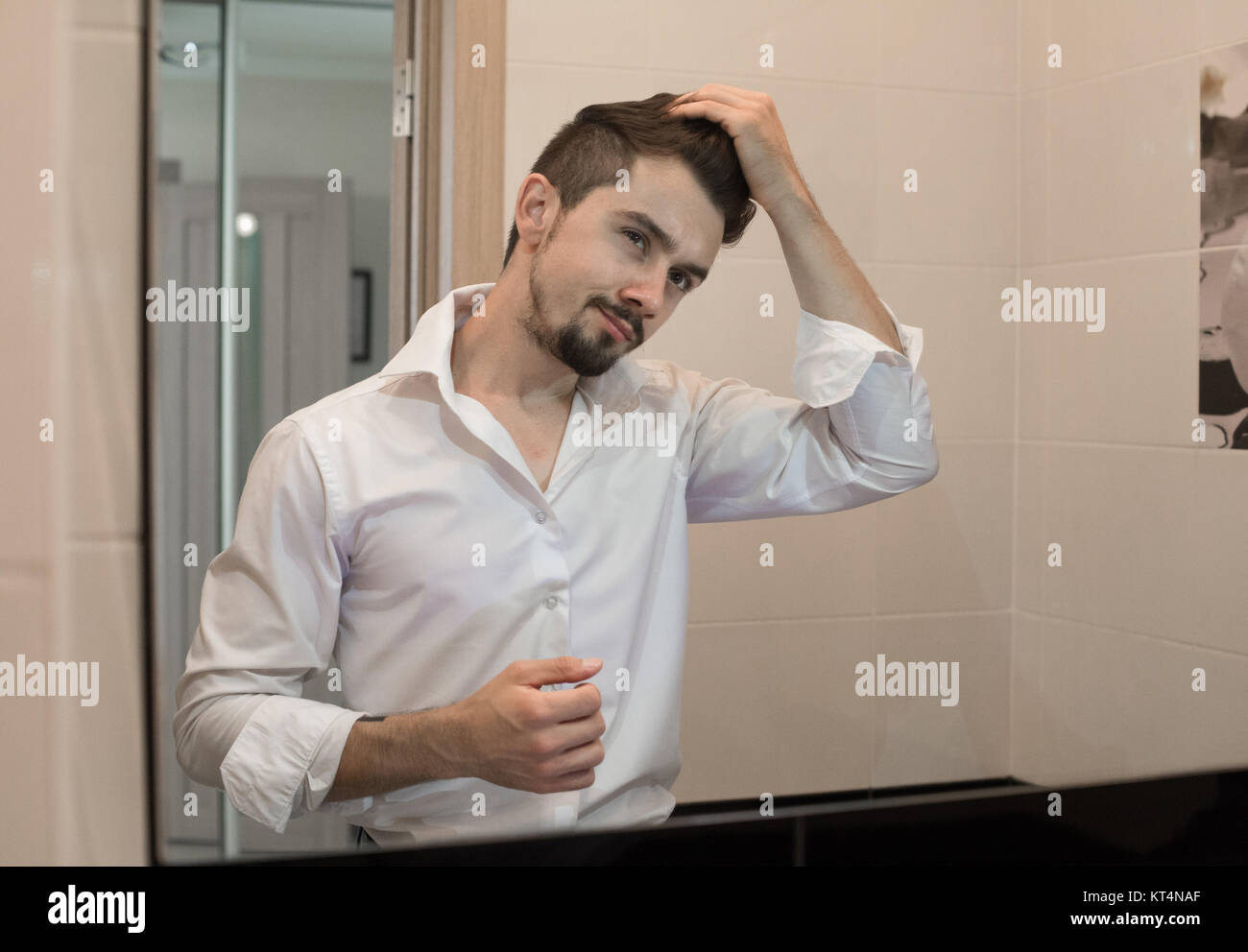 Portrait von stilvollen Heiter froh glücklich aussehenden fröhlicher junger Mann seine Haare kämmen und Lachen. Mann kümmern sich über sein Haar. Ein Mann kümmert sich um die Haare. Sexy Kerl Pflege von seinem Aussehen. Stockfoto