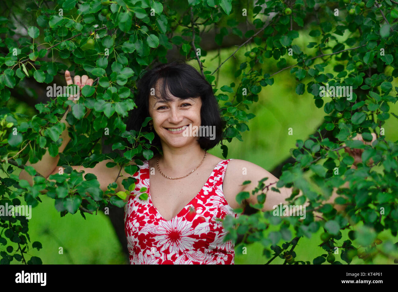 Die glücklichste Frau der Welt mit unglaublich schönen weißen Lächeln in grüne Bäume im Sommer. Schöne attraktive hübsche Frau mit weißen Lächeln stehen auf grün Hintergrund im Freien. Stockfoto