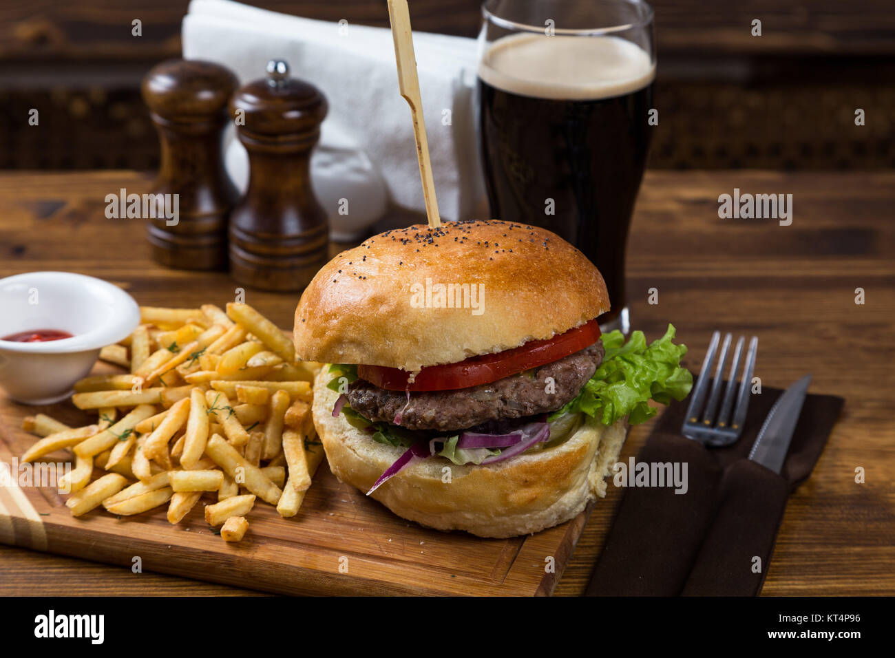 Hot Burger auf Holzbrett mit dunklem Bier Stockfoto