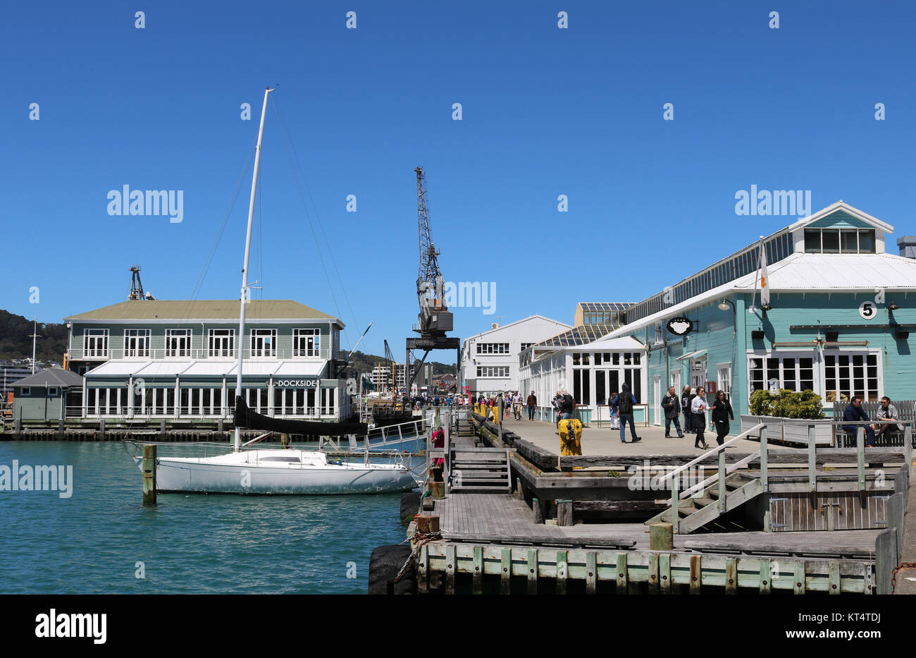 Verschiedene Leute, Touristen und Einheimische, Wandern am Wasser vorbei an Lagerhallen an der Queens Wharf in den Hafen von Wellington, Nordinsel, Neuseeland Stockfoto