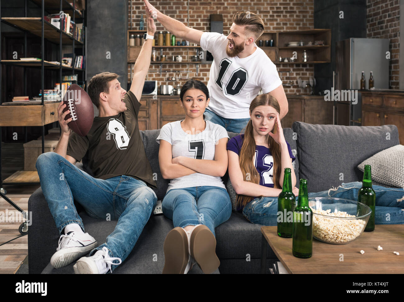 Junge Frauen in der Nähe von aufgeregt Männer unterstützen Lieblingsfußballmannschaft zu Hause sitzen gelangweilt Stockfoto