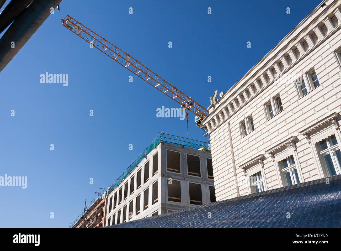 Baustelle mit Altbau und Neubau nebeneinander, durch einen Kranausleger optisch getrennt Stockfoto