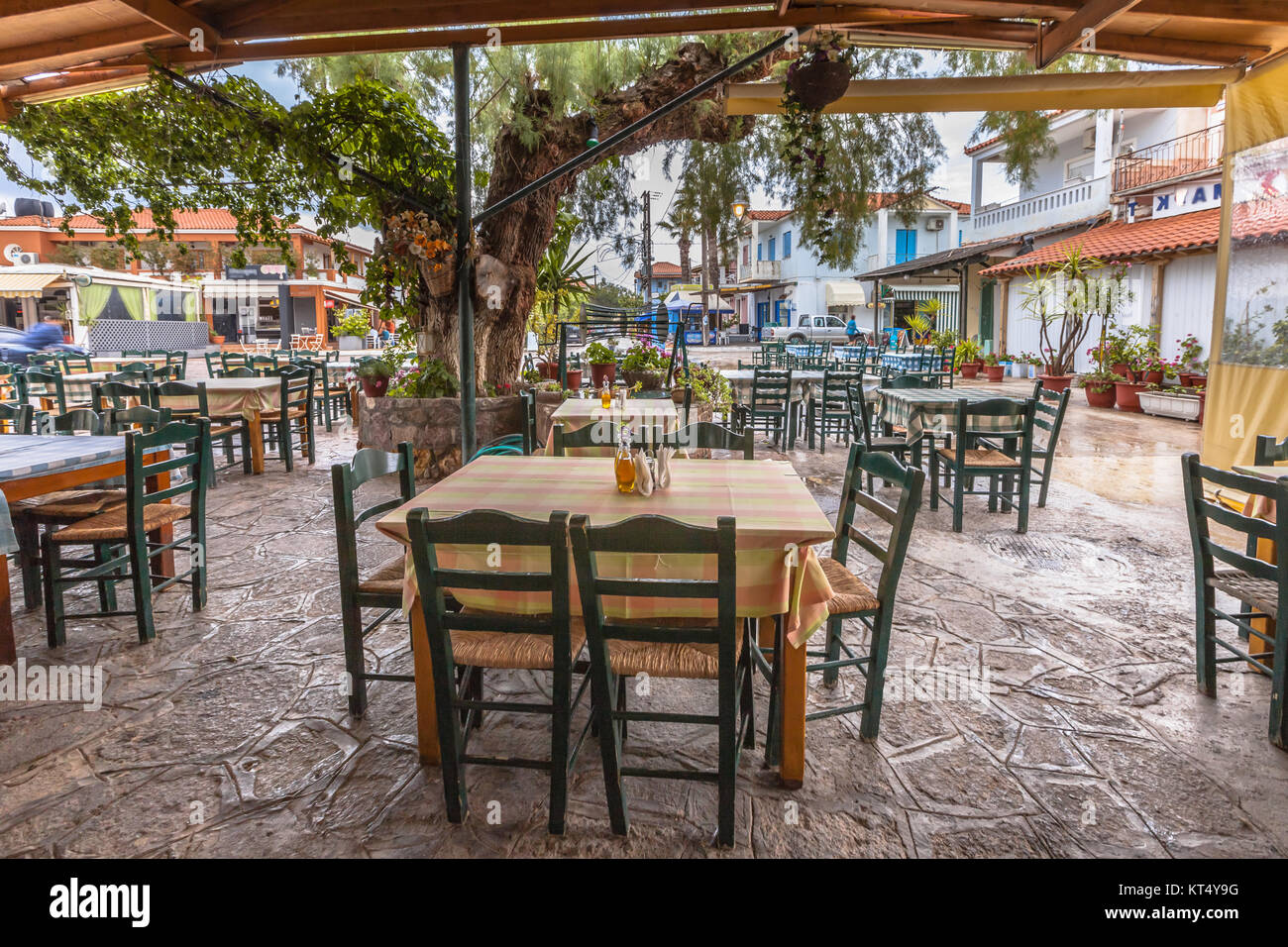 Traditionelles Dorf Restaurant Terrasse mit Holztischen und Stühlen unter einem riesigen Baum Stockfoto
