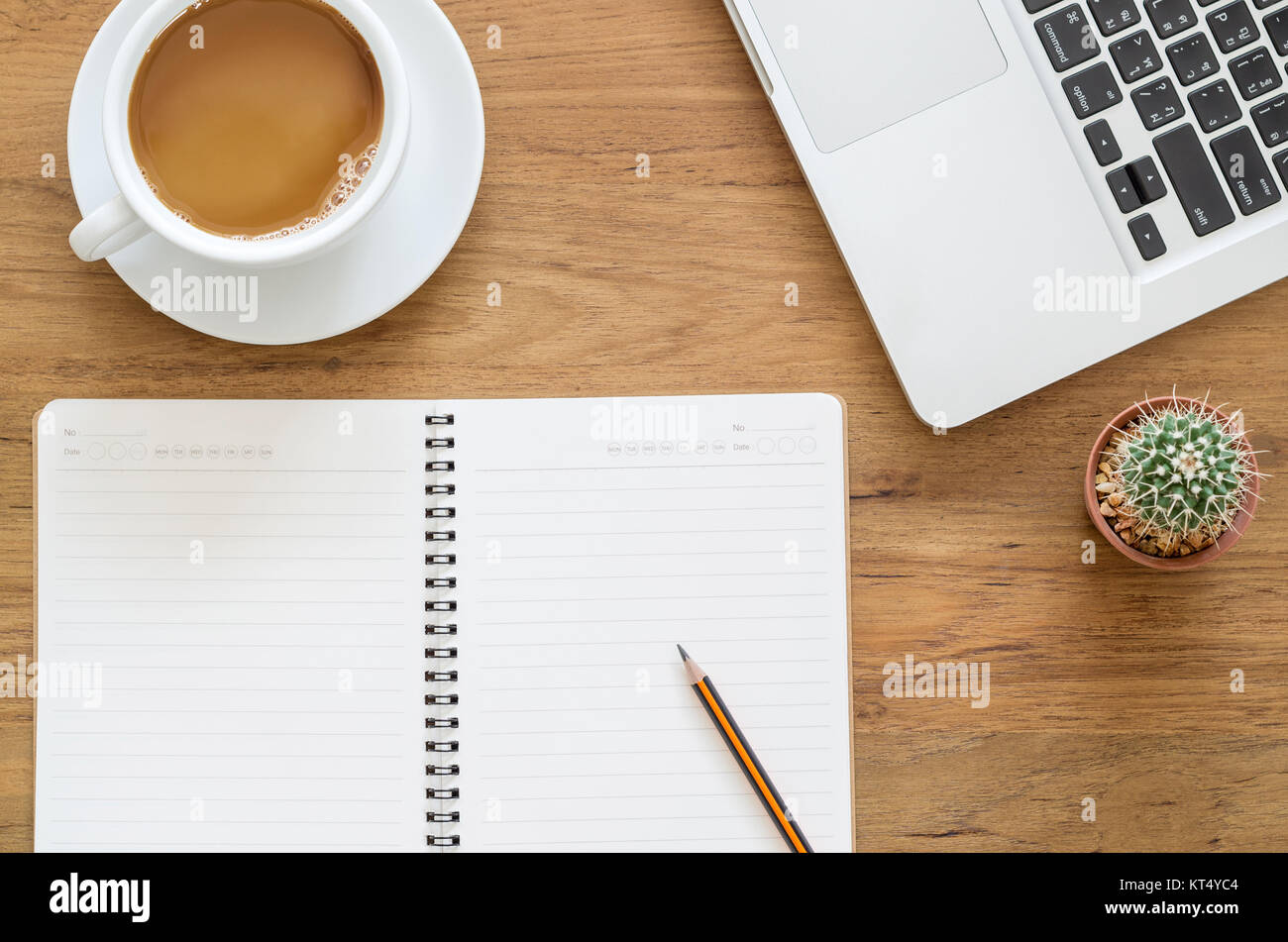 Schreibtisch aus Holz Tisch mit Notebook, Computer, Laptop, Bleistift, Kakteen und Tasse Kaffee. Ansicht von oben mit der Kopie. Stockfoto