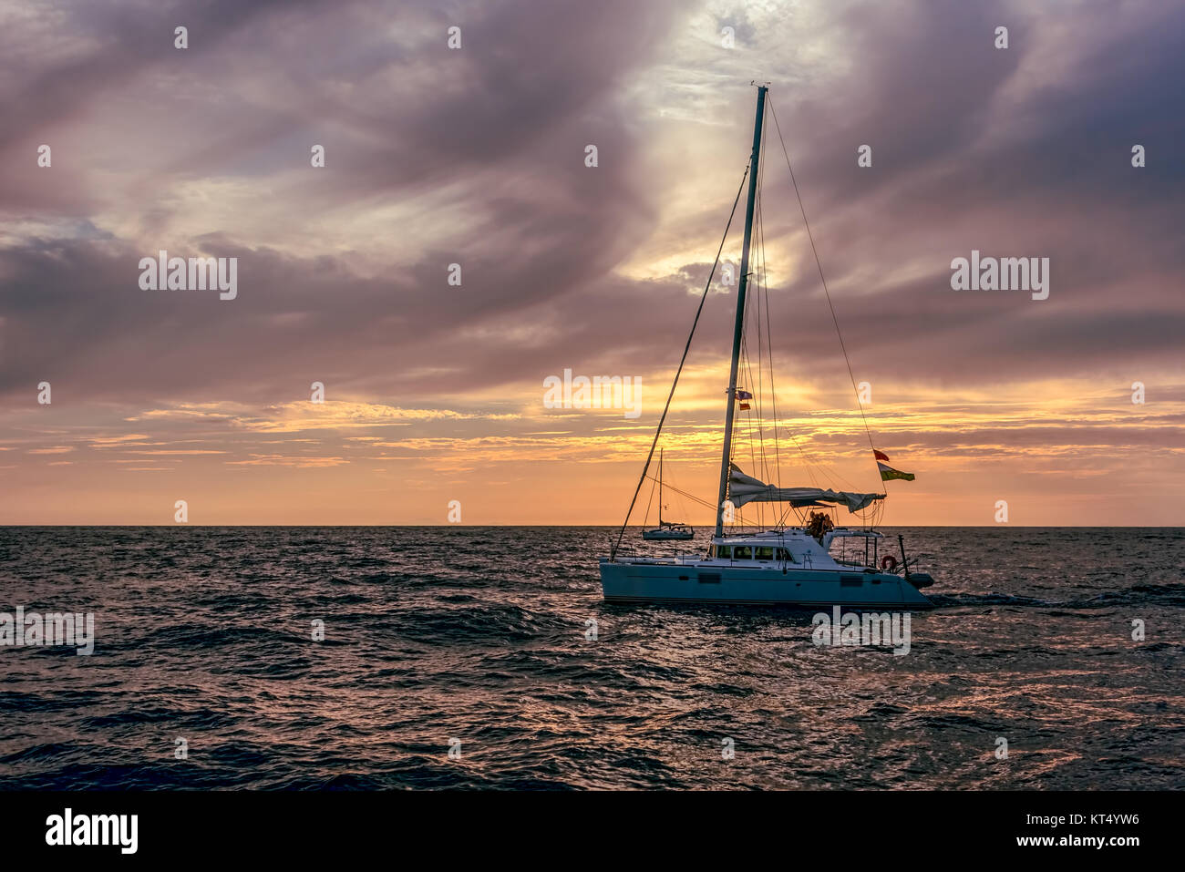 Segelboot auf offener See bei Sonnenuntergang bei bewölktem Himmel Stockfoto