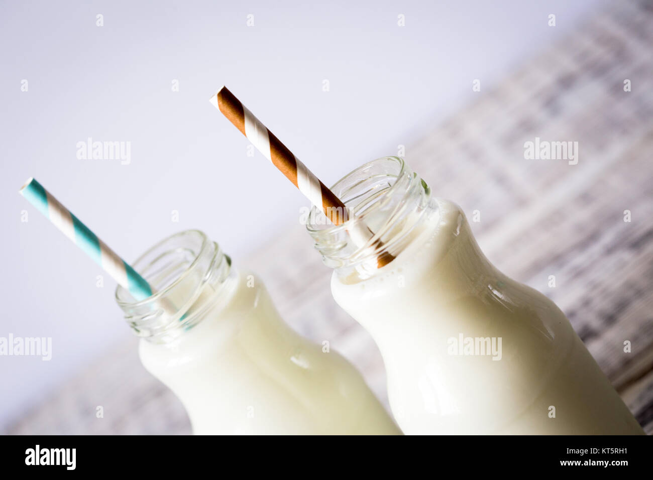 Zwei Flaschen Milch mit gestreifte Trinkhalme stehend auf alten Tisch ...