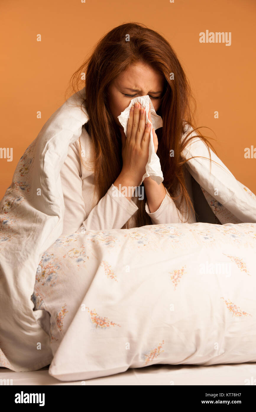 Krankheit Grippe - junge Frau auf dem Bett liegend angesteckt mit Allergie blasen Ihre Nase Stockfoto