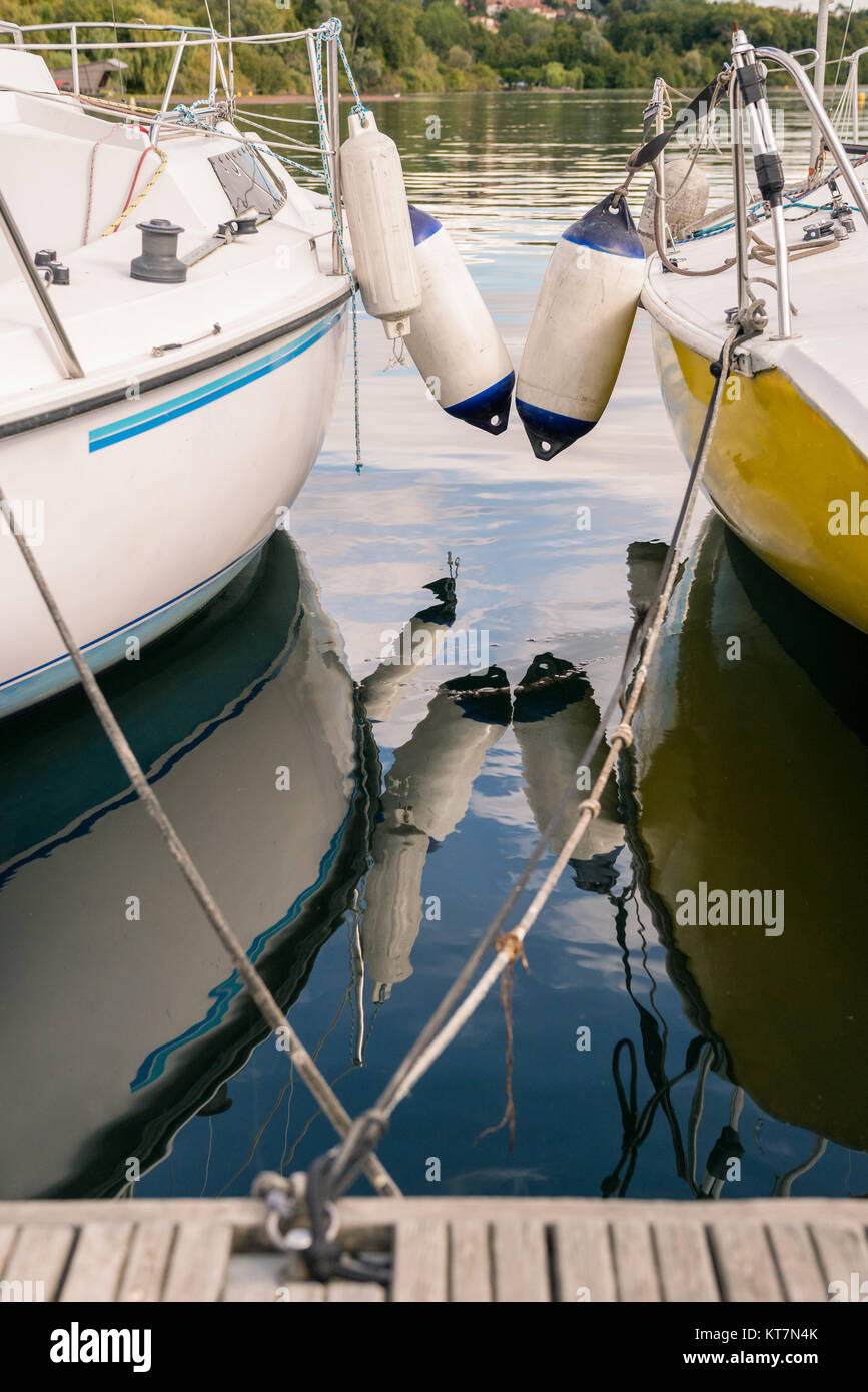 Segel Boote im Wasser Dock an der hölzernen Floating touristische Pier im sonnigen Sommermorgen widerspiegelt. Stockfoto