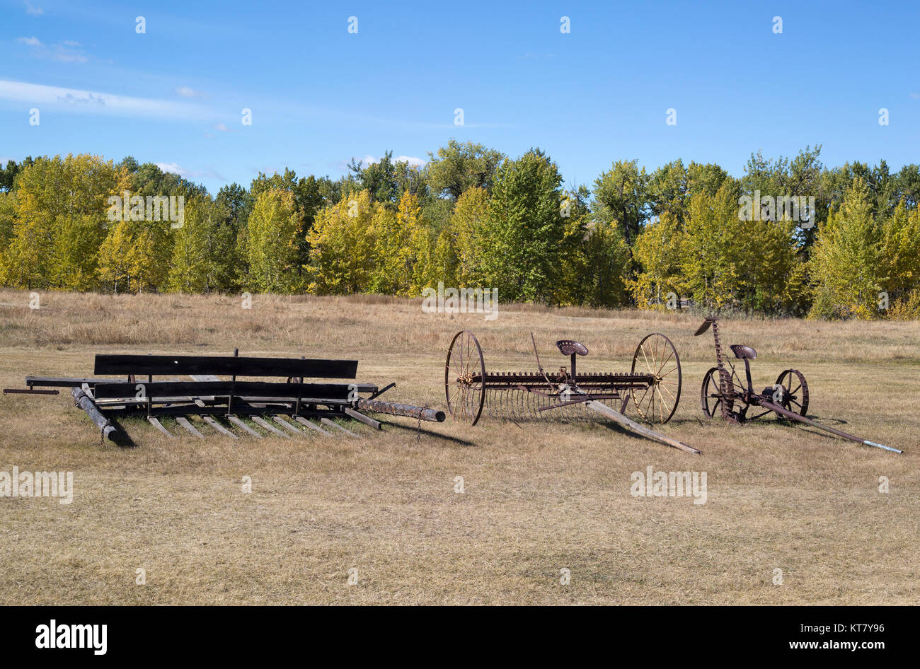 Alte landwirtschaftliche Maschinen, darunter ein rostiger antiker Kultivator auf einem Feld in der Bar U Ranch National Historic Site, Alberta, Kanada Stockfoto