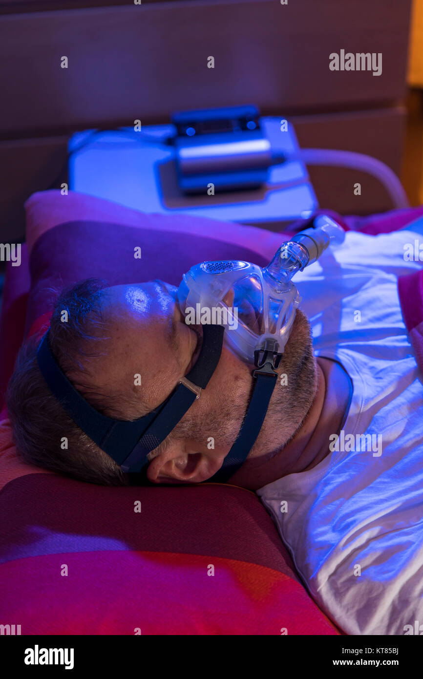 Ein Mann mit Schlafapnoe Syndrom, trägt eine CPAP-Maske beim Schlafen, Atemmaske, die Luft in die Atemwege durch Überdruck, der Luftwege verhindert Stockfoto