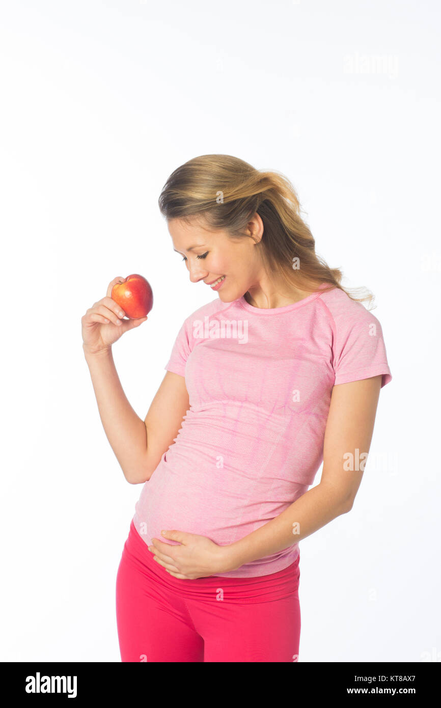 Schwangere Frau mit einem roten Apfel und ihr Stoß gegen einen weißen Hintergrund berühren Stockfoto