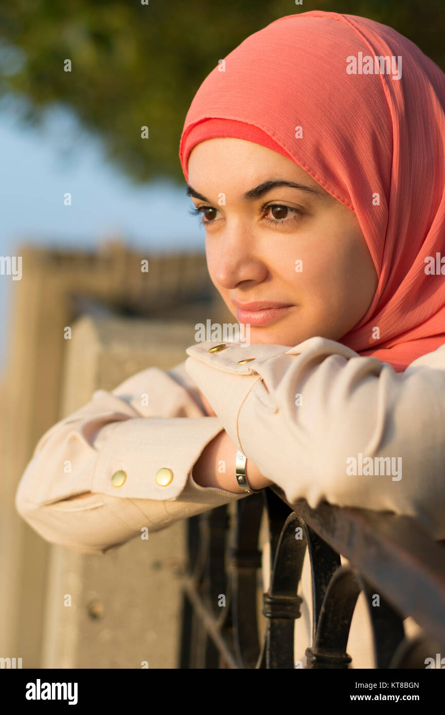 Schöne muslimische Frau lehnte sich auf den Zaun weg schauen im Freien Stockfoto