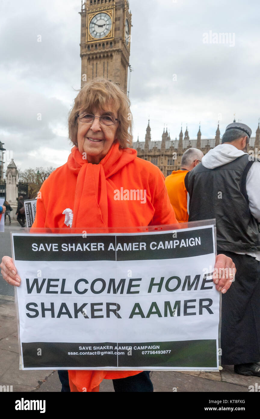 Speichern Shaker Aamer Kampagne Stuhl Freude Hurcombe hält ein Plakat:  "Willkommen zuhause, Shaker Aamer' an Ihre Feier seiner Freigabe gegenüber  Parlament, wo die Gruppe eine wöchentliche Mahnwache für seine relese  gehalten haben
