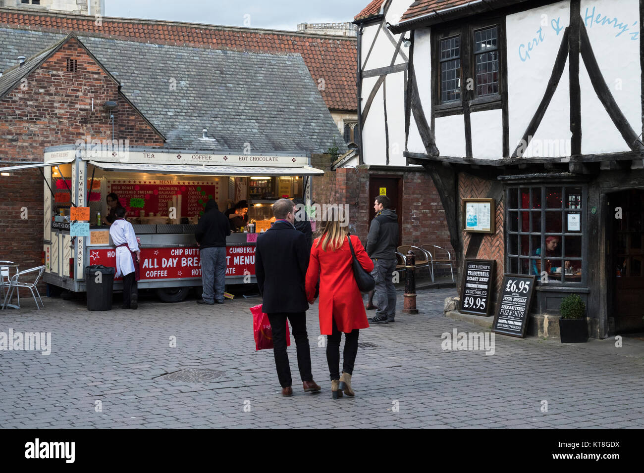 Kunden kaufen Street Food & Menschen mit Tüten durch Shambles Markt, ein historischer Markt in York, North Yorkshire, England, UK. Stockfoto
