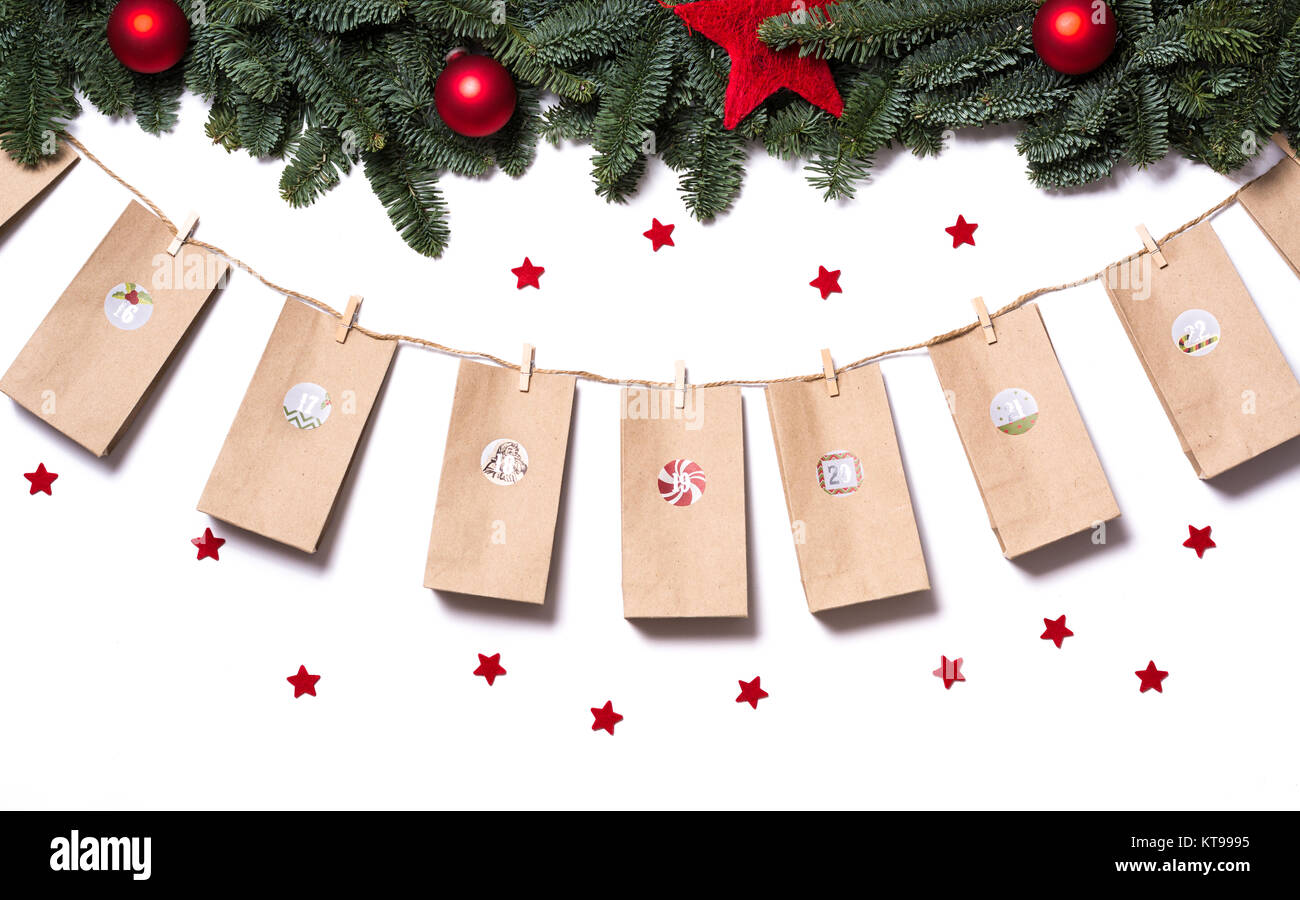 Handgefertigte Adventskalender Mit Papiertuten Und Aufkleber Hangen Von Tannenzweigen Und Roten Sternen Auf Einem Weissen Hintergrund Gebastelt Stockfotografie Alamy