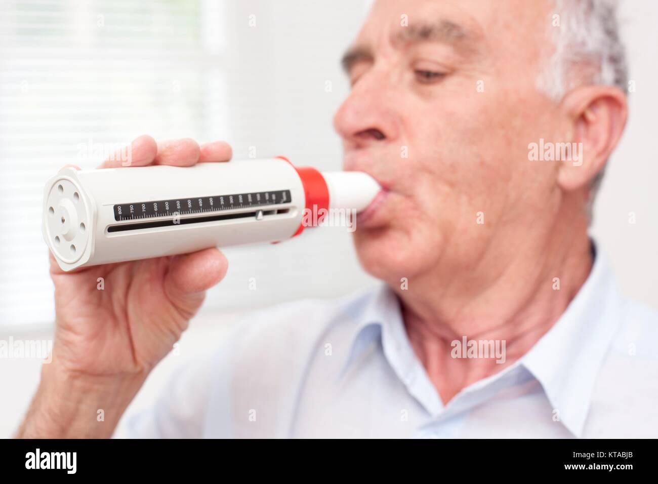 Ältere Menschen beim Ausatmen in eine peakflow Reader. Stockfoto