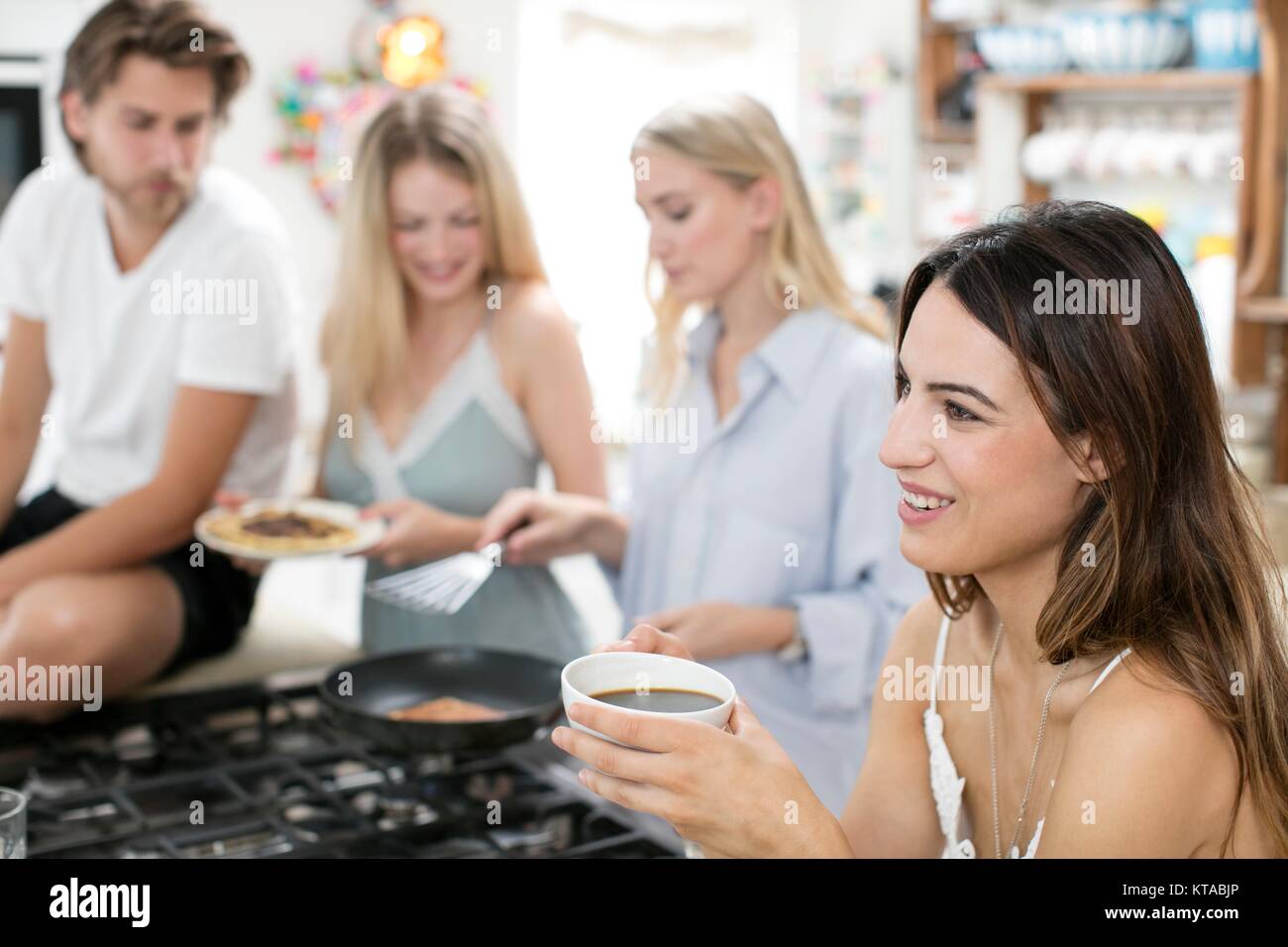 Junge Frau trinkt Kaffee in der Küche mit Freunden. Stockfoto
