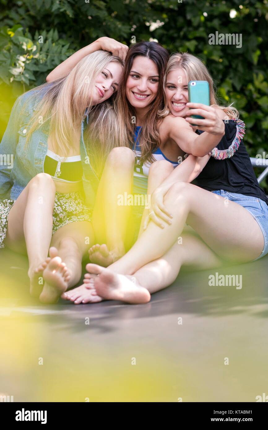 Drei junge Frauen selbst fotografieren mit Smartphone. Stockfoto